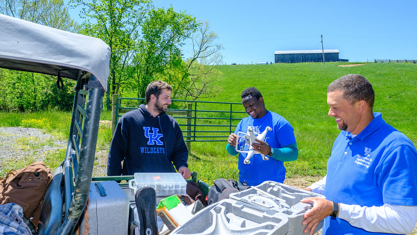 People with the Department of Biosystems and Engineering examine equipment in a field